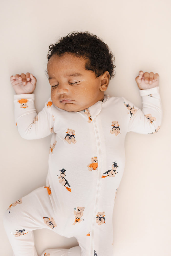 Baby sleeping in Zippered Footie in Halloween Teddy print on a beige background