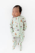 Baby sleeping in a green and white striped zippered footie with colorful Harry Potter patterns on a white background