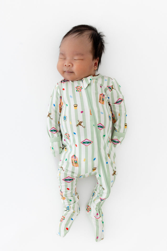 Baby sleeping in a green and white striped zippered footie with colorful Harry Potter patterns on a white background