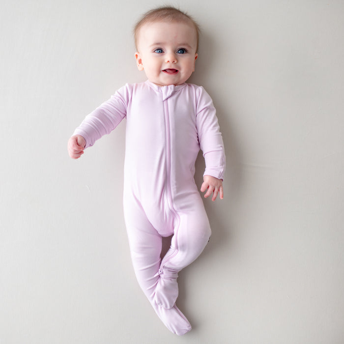 Baby smiling wearing a light purple zippered footie