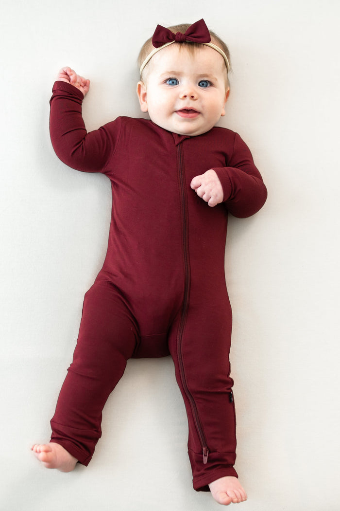 Infant model wearing the Zippered Romper in Burgundy with matching tiny nylon bow